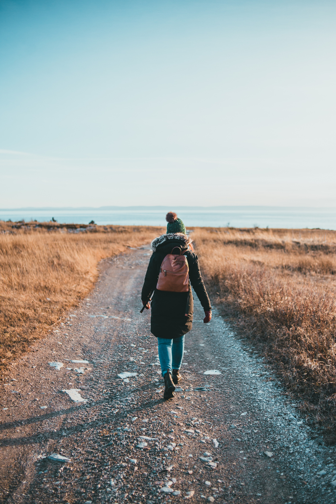 Unrecognizable female traveler strolling on path towards ocean